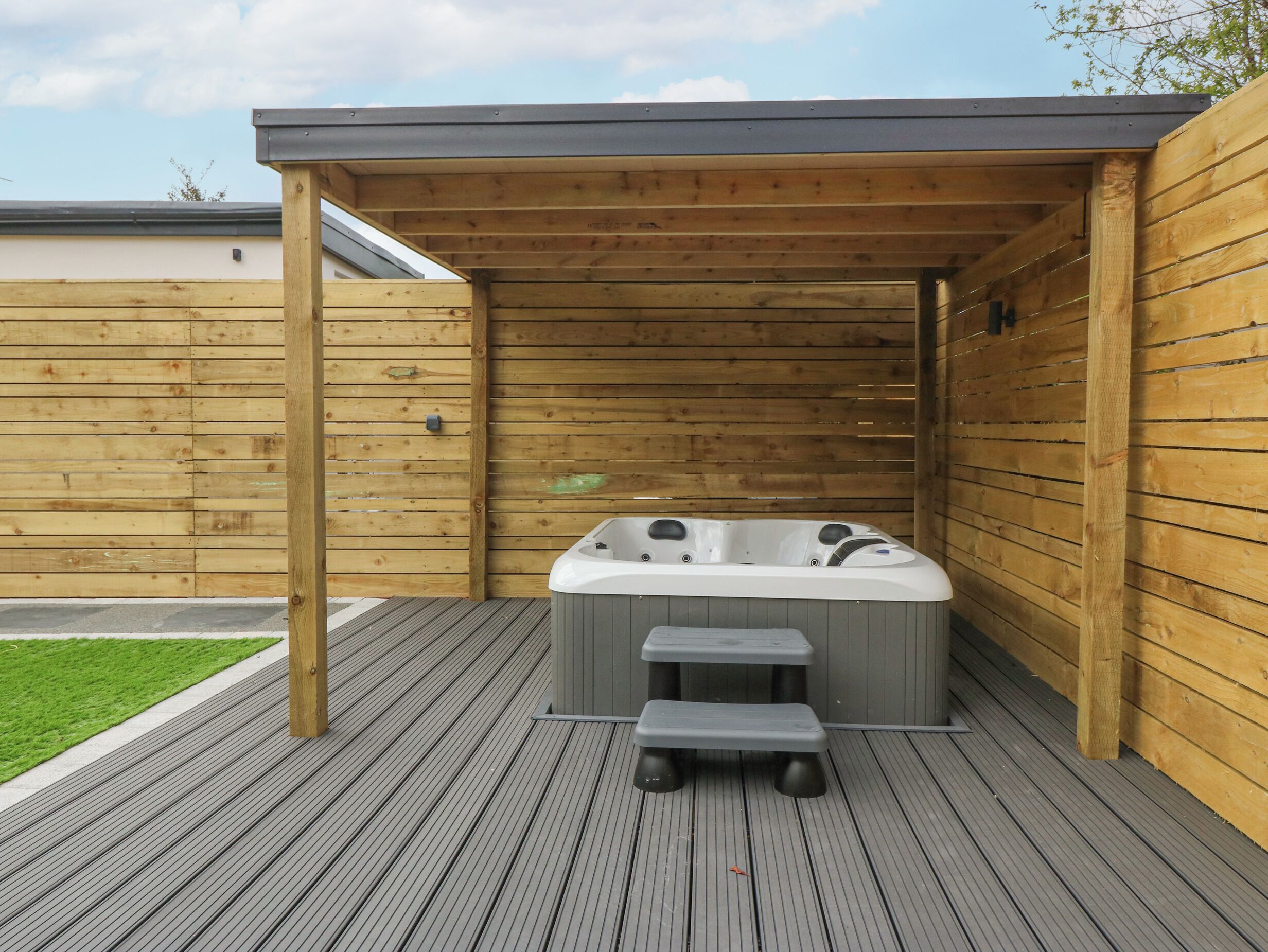 A wooden deck with a hot tub and steps.