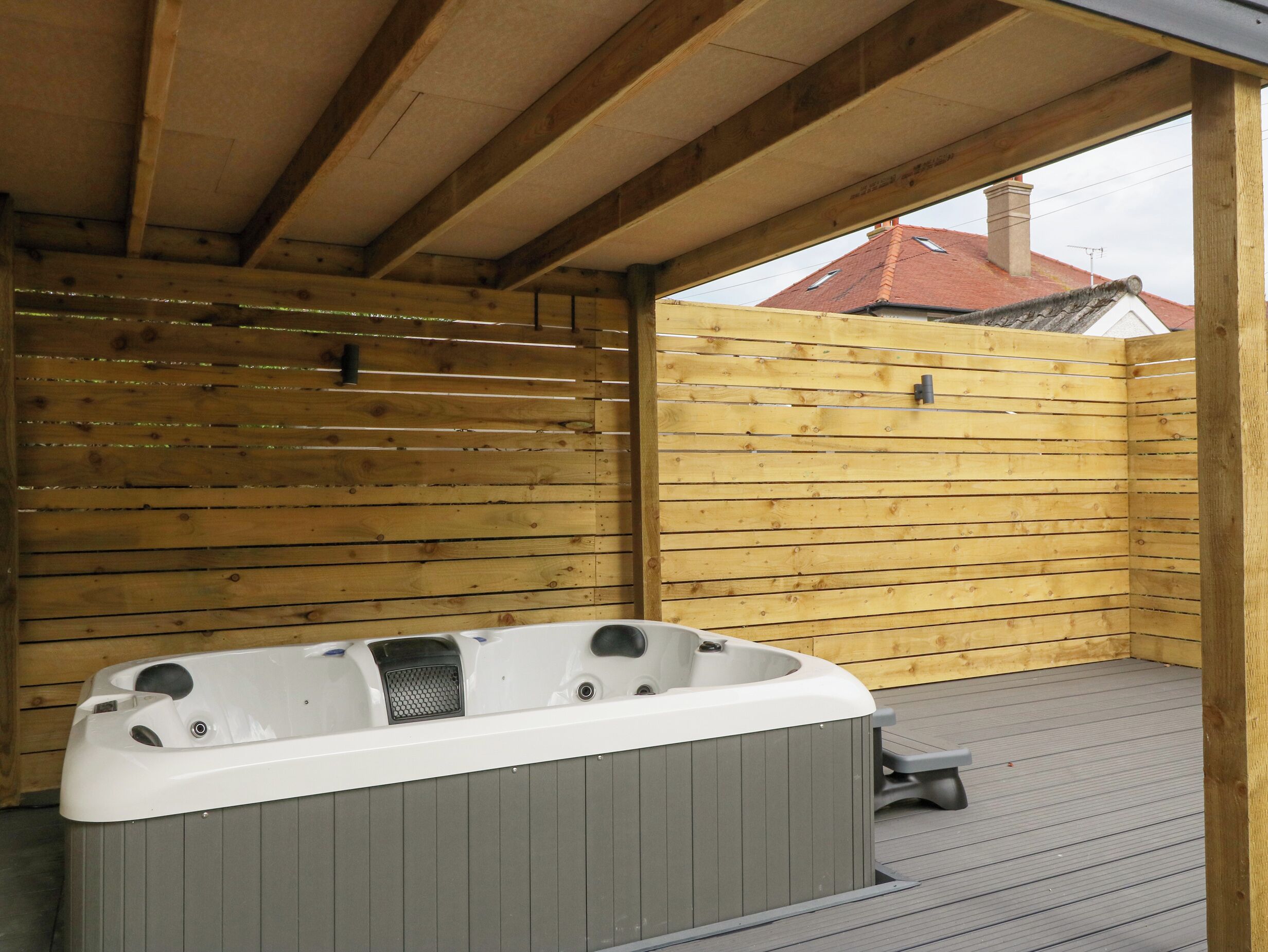 A wooden deck with a hot tub and a wooden fence.