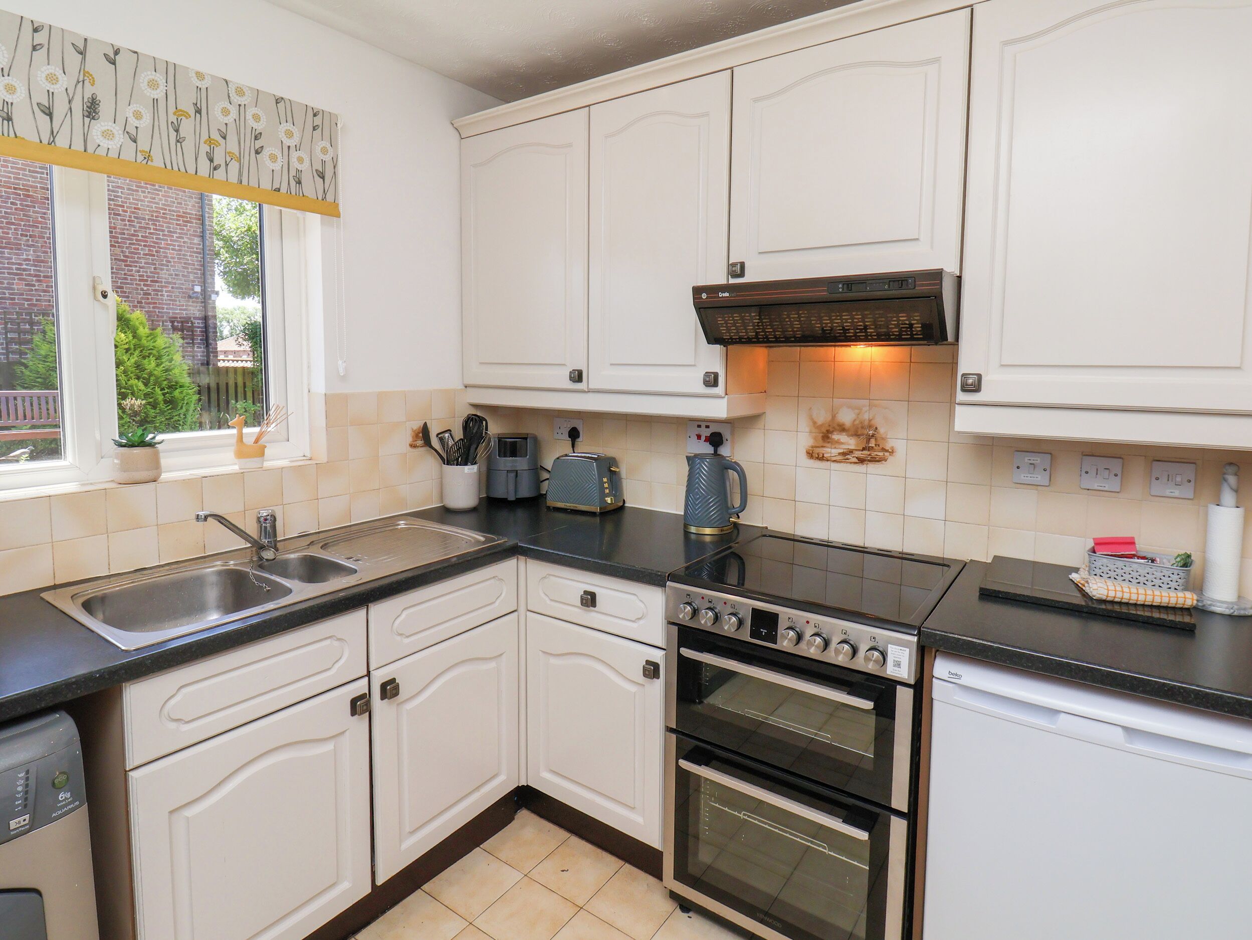 A kitchen with white cabinets, a double oven, a coffee maker, and a toaster.