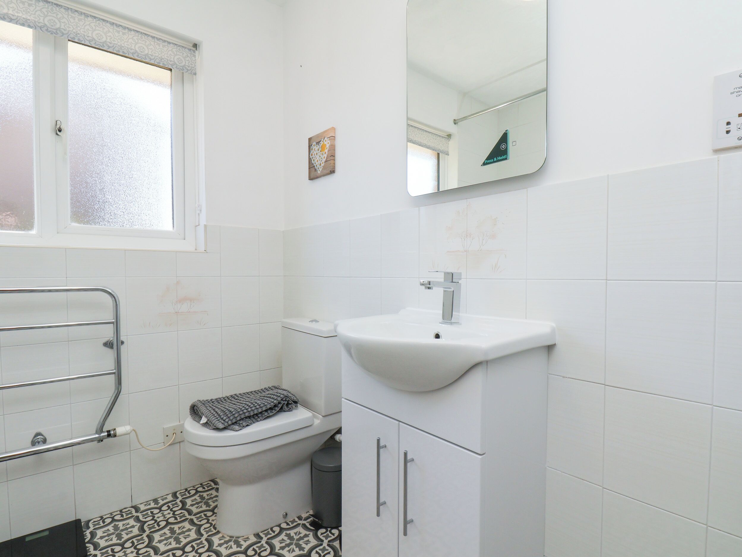 A bathroom with a toilet, a sink, a mirror, and a window.