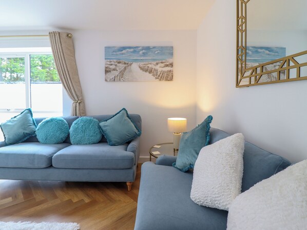 A modern living room with a blue sofa, a white fluffy throw, and a lamp. - Blackrock Gem (Porthmadog)