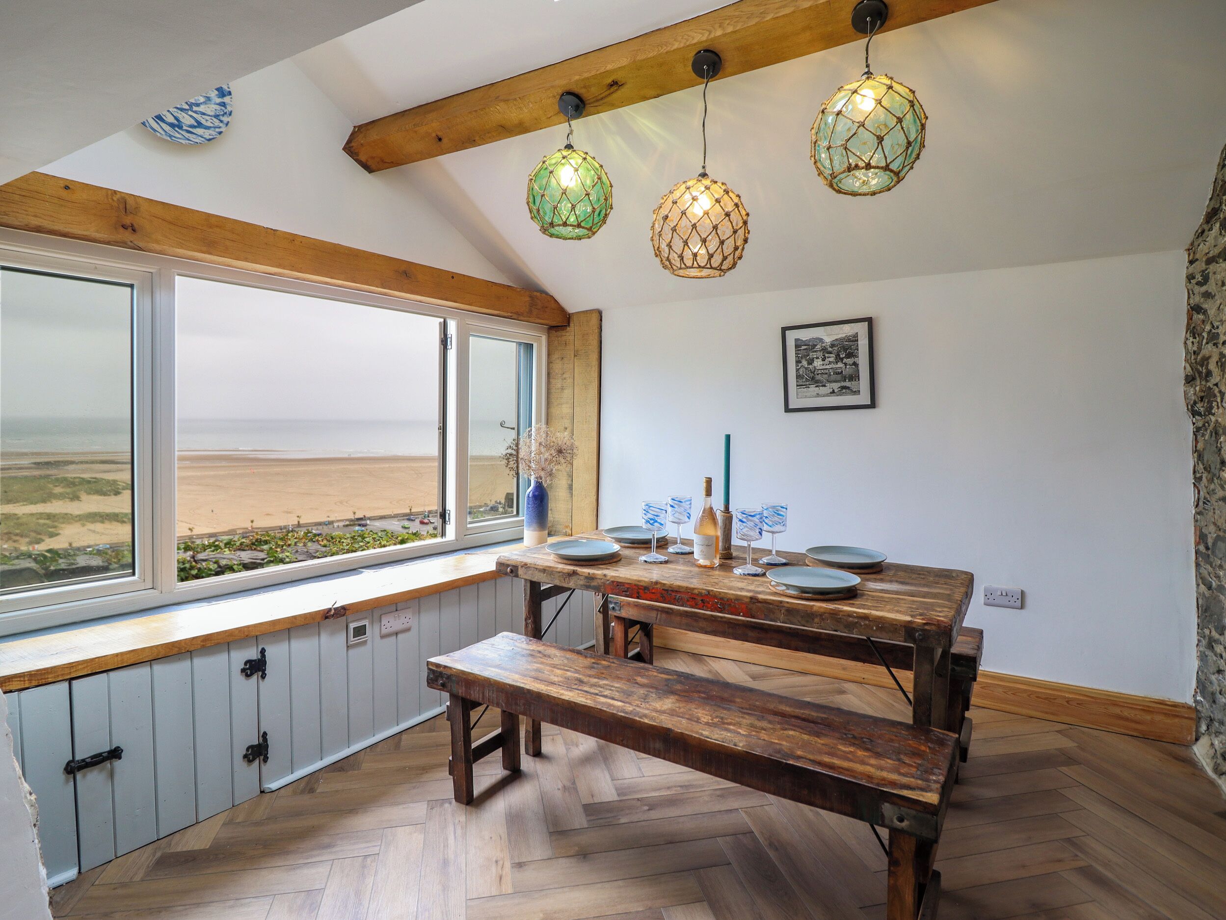 A dining area with a wooden bench, a table, and hanging lights.