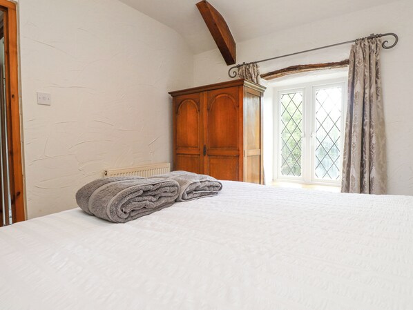 Ein Schlafzimmer mit einem Bett, einem Holzschrank und einem Fenster mit Vorhängen.