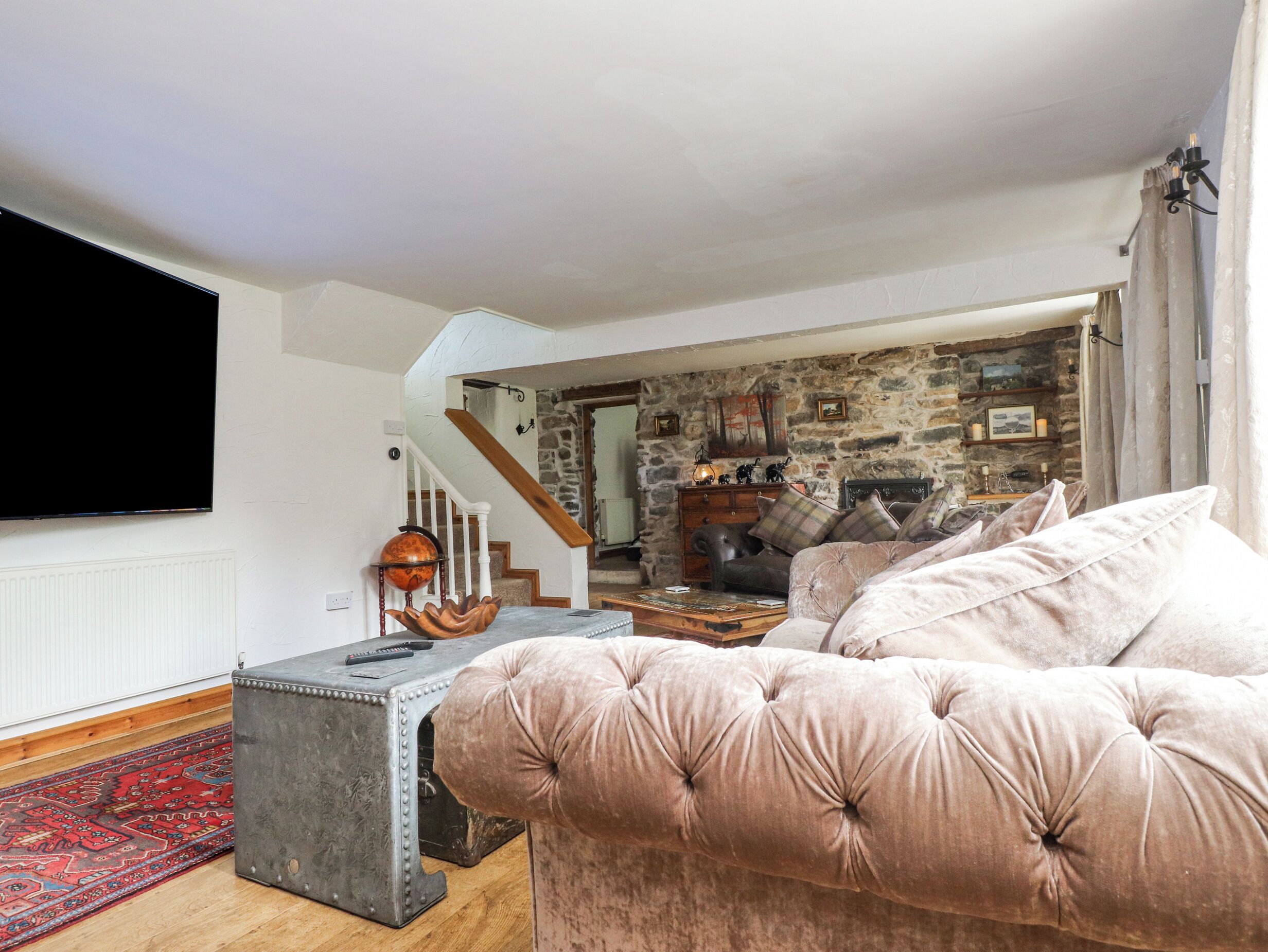 A living room with a large flat-screen TV, a plush sofa, a coffee table, and a patterned rug.