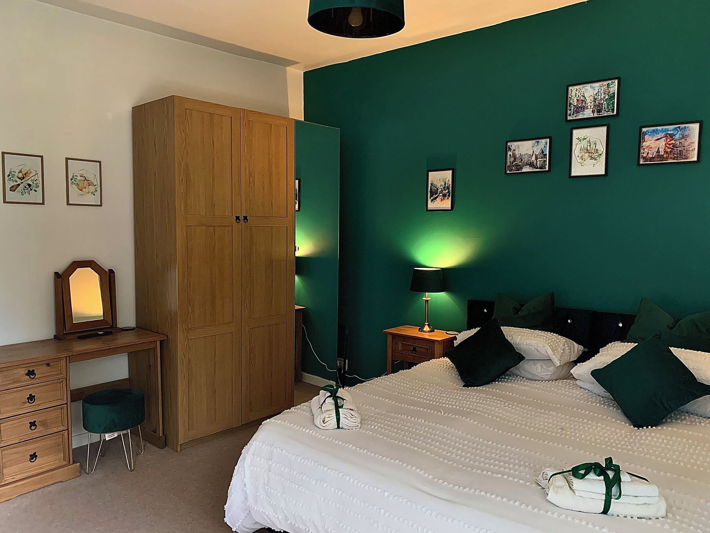 A bedroom with a bed, a desk, a wardrobe, and a nightstand.