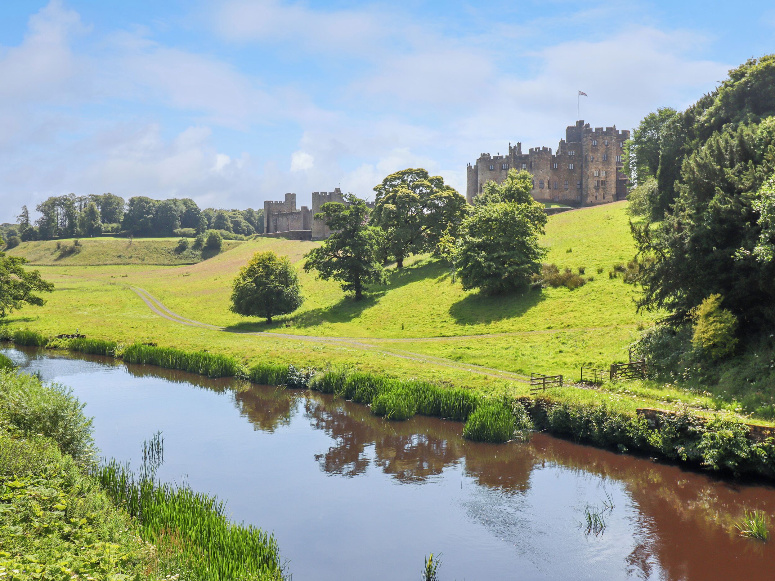 A castle on a hill with a river in the foreground.
