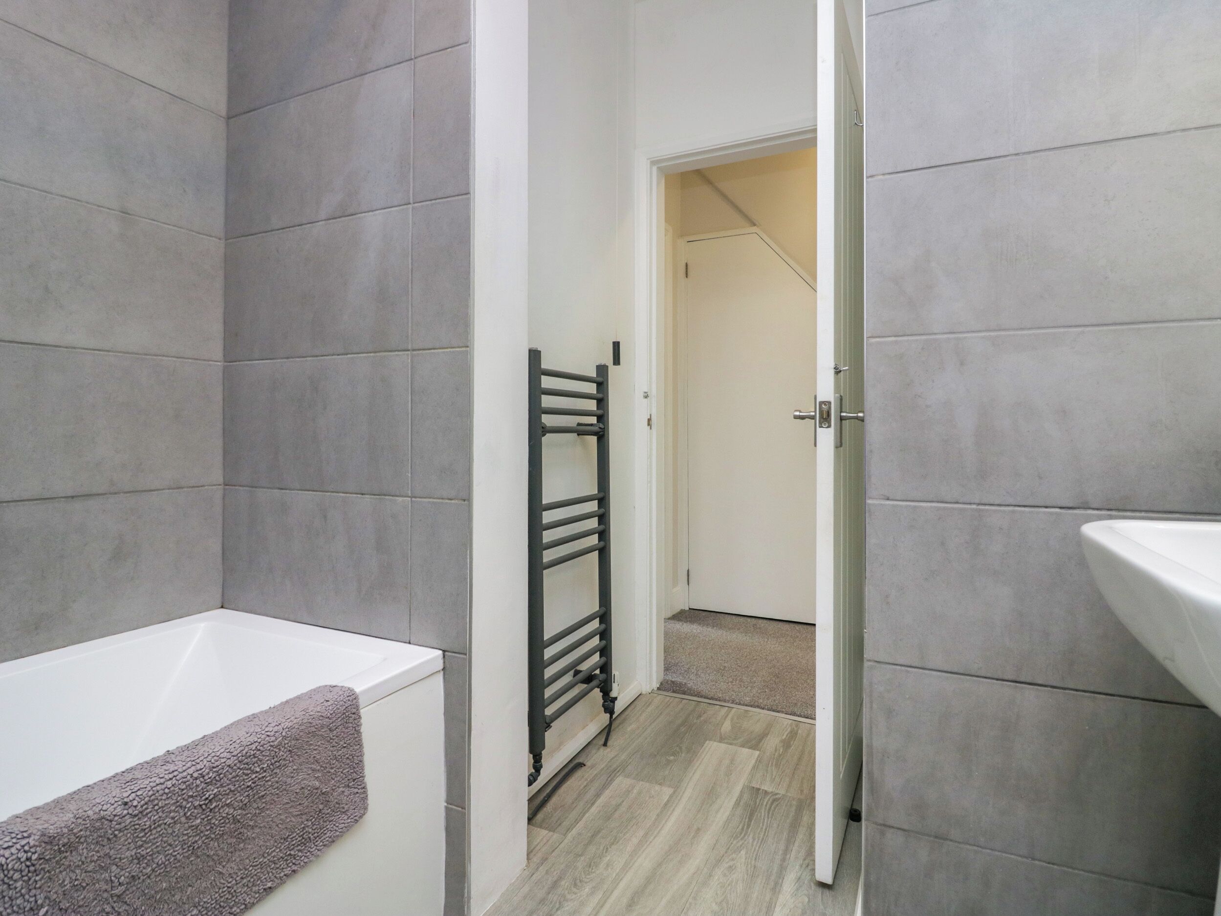 Ein modernes Badezimmer mit einer weißen Badewanne, einem Handtuch und einem schwarzen Handtuchhalter.