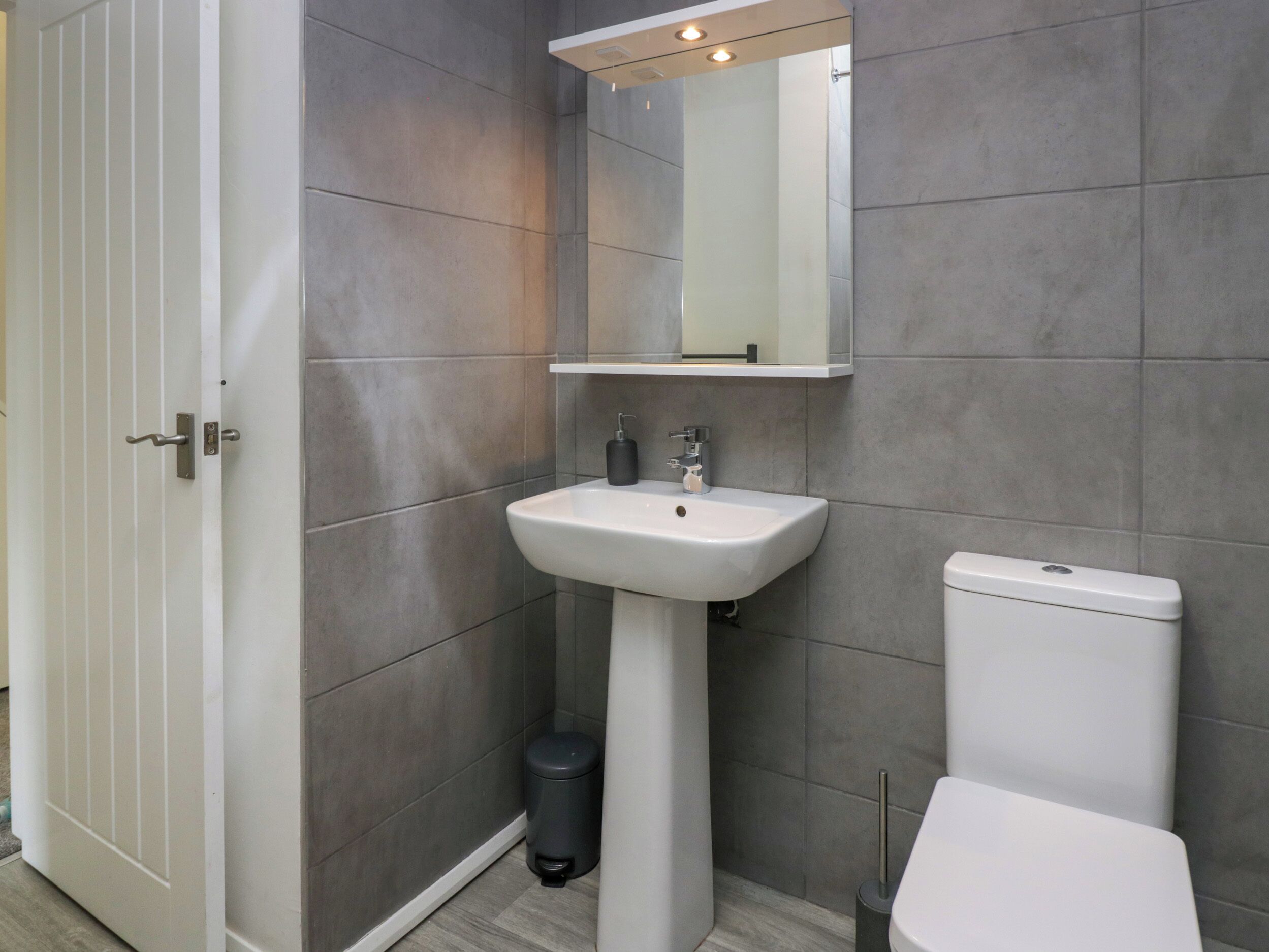 Ein modernes Badezimmer mit Waschbecken, Spiegel und Toilette in Weiß.