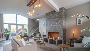 Una sala moderna con una pared de acento de piedra, una chimenea y una escalera que sube a un nivel superior.