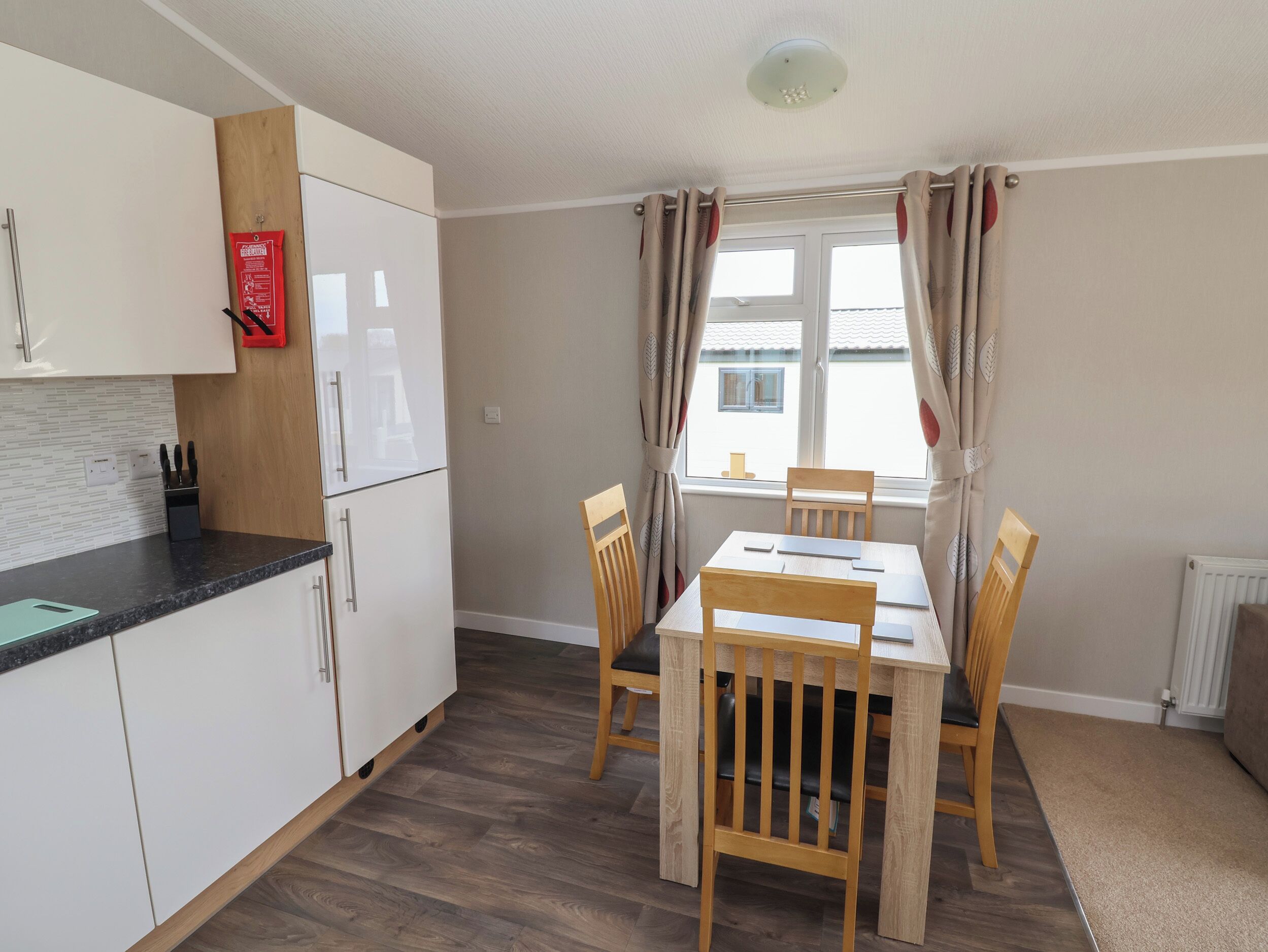 A compact kitchen with white cabinets, a black countertop, and a wooden dining table with four chairs.