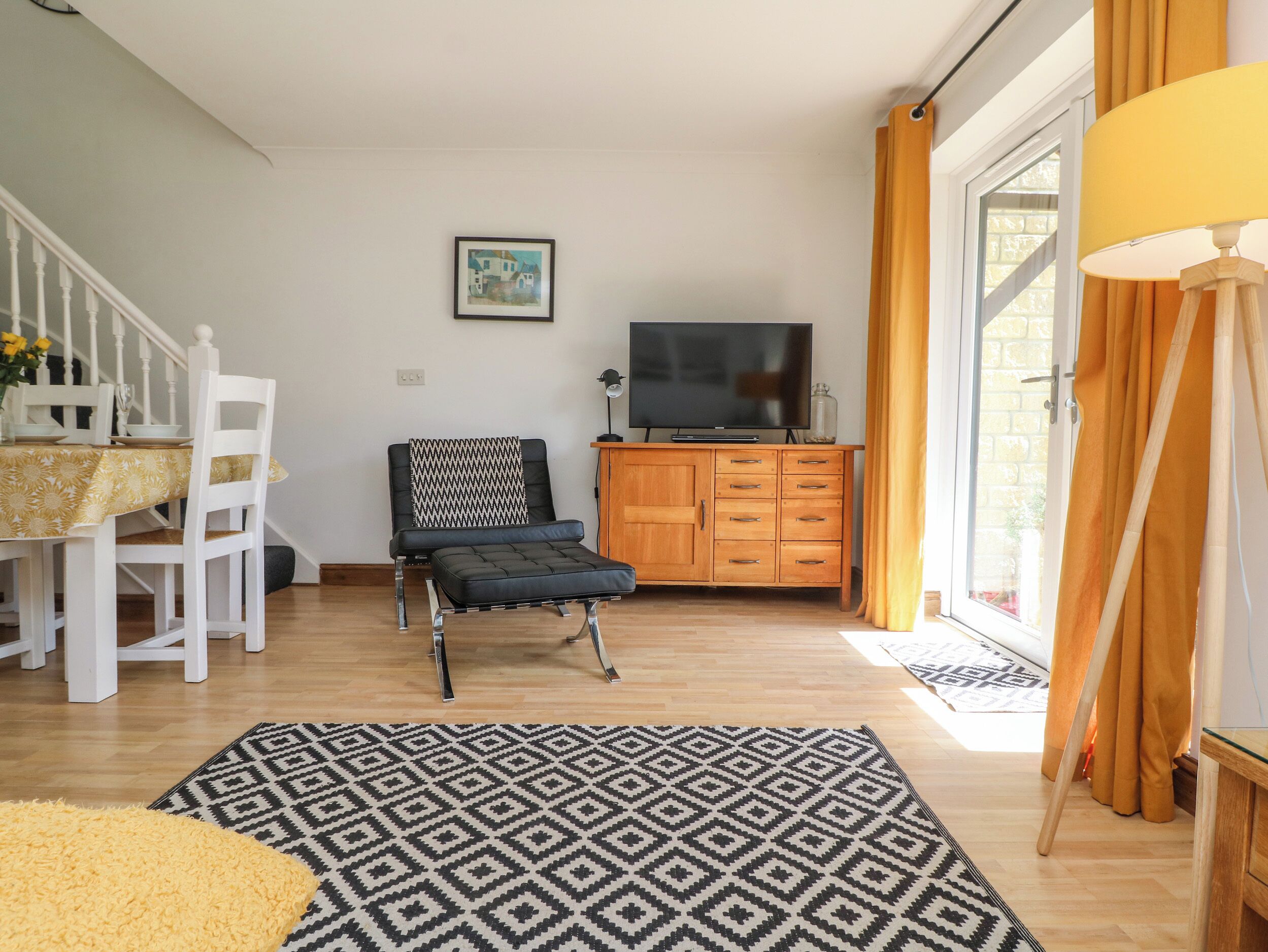 A living room with a sofa, a TV, a wooden cabinet, and a dining area with chairs and a table.