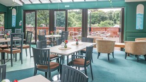 Un restaurante con terraza, ventanas amplias y vistas al paisaje exterior.