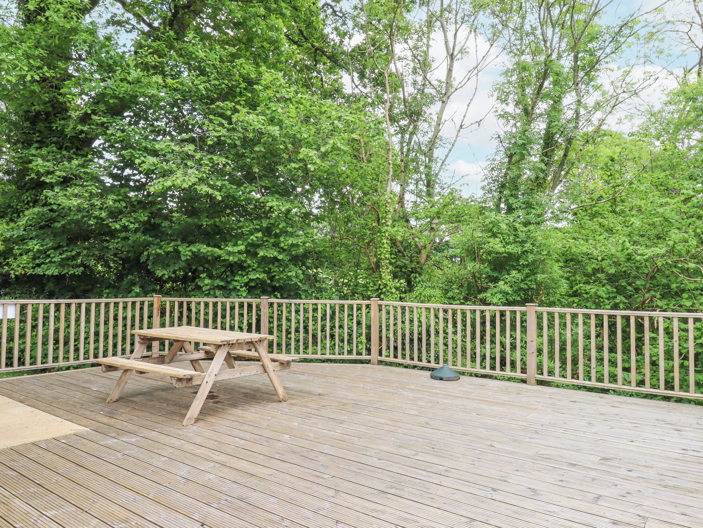 A wooden deck with a picnic table and a metal lamp post.