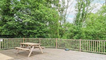 A wooden deck with a picnic table and a metal lamp post.