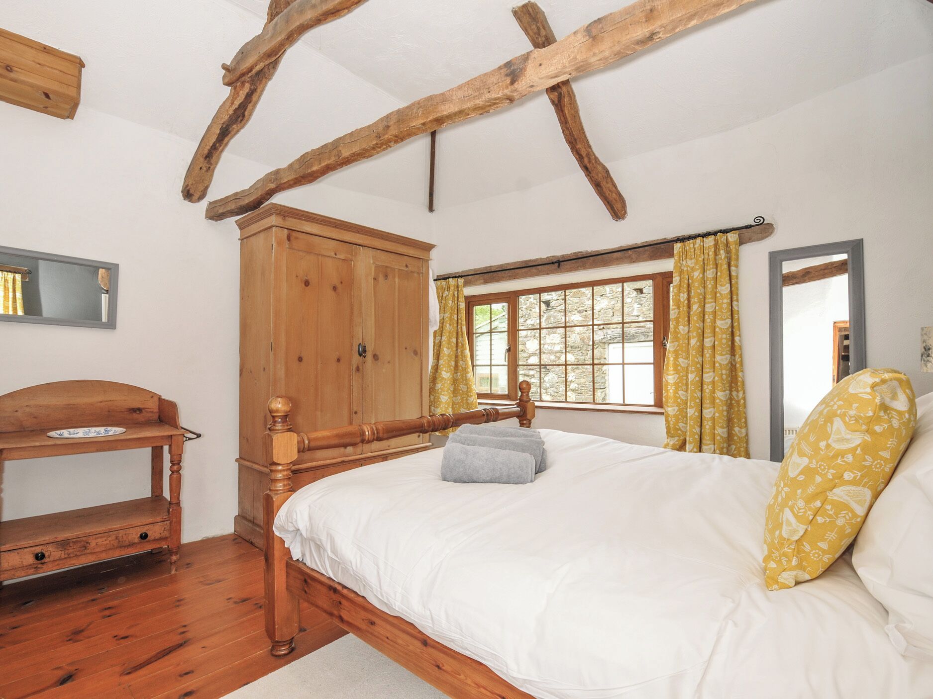 Ein Schlafzimmer mit einem hölzernen Bett, einem Schrank aus Holz, einer Holzbank und einem Fenster mit Vorhängen.