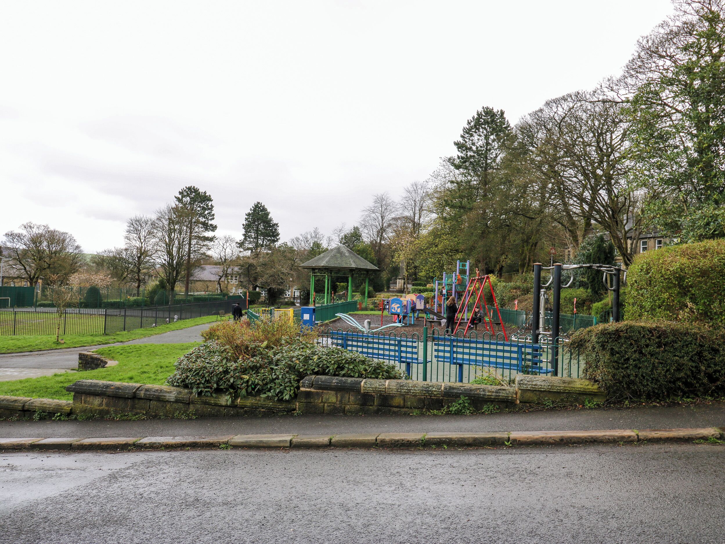 A park with playground equipment, a gazebo, and a fenced area.