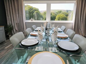 A dining area with a glass table set for six, chairs, and a view of greenery through the window. - The Old Telephone Exchange (Huddersfield)