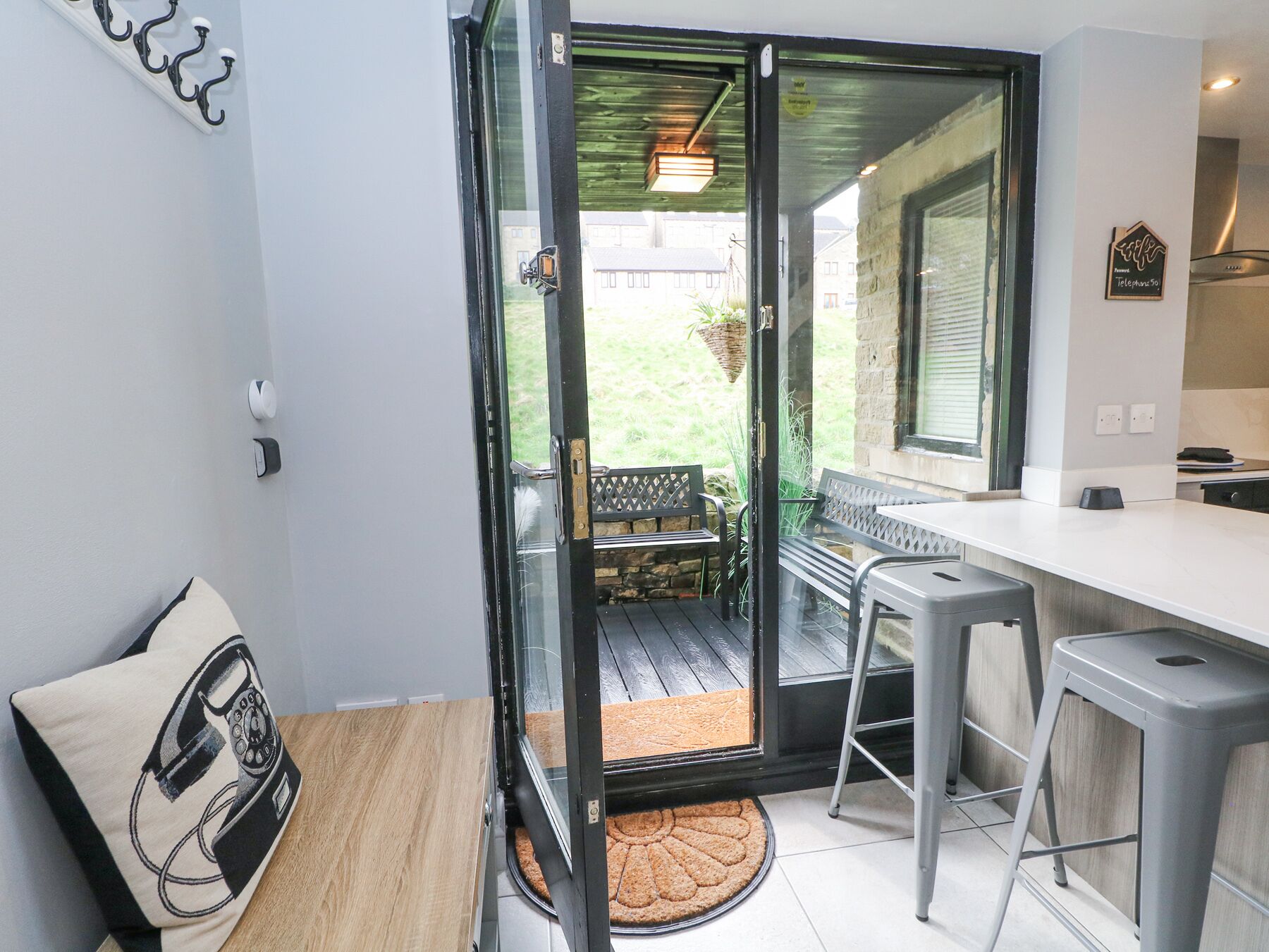 Una cocina moderna con encimera blanca y horno empotrado. Hay un comedor con banco y mesa.