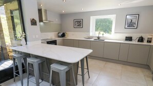 A modern kitchen with a central island, grey bar stools, a microwave, and a coffee machine. - The Old Telephone Exchange (Huddersfield)