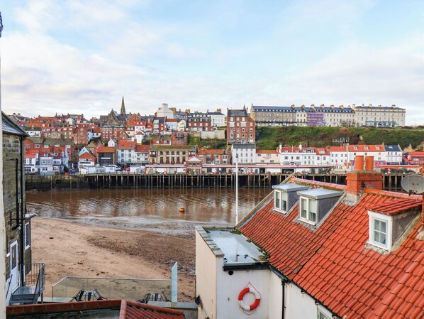 A coastal town with buildings along the waterfront, including a pier and a sandy beach area. - Kitty's Cottage (Whitby)