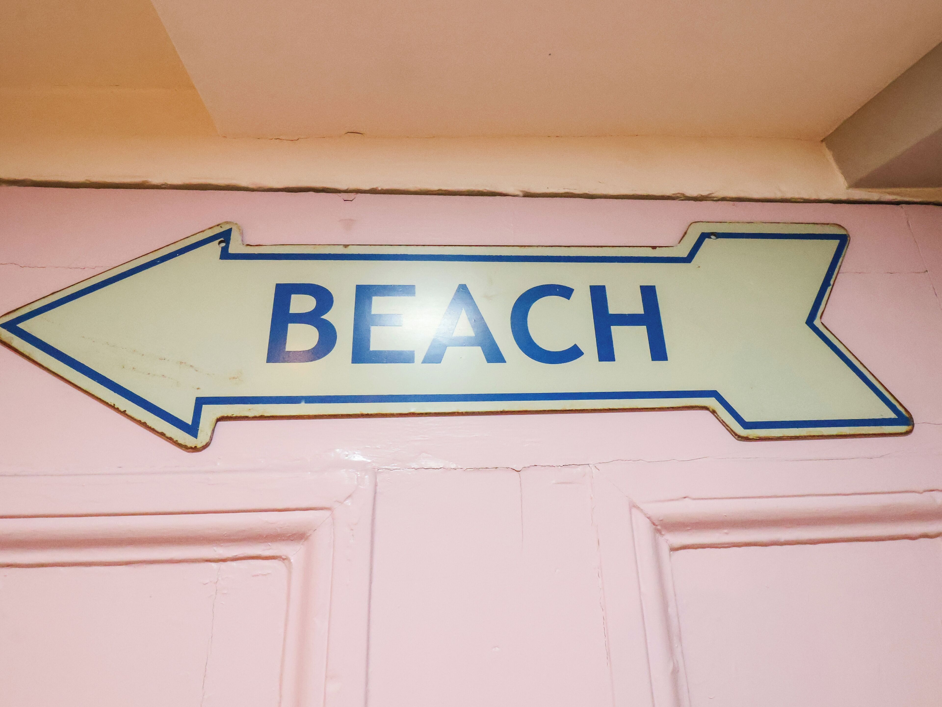 Un panneau de signalisation indiquant la direction de la plage, avec le mot « PLAGE » et une flèche pointant vers la gauche.