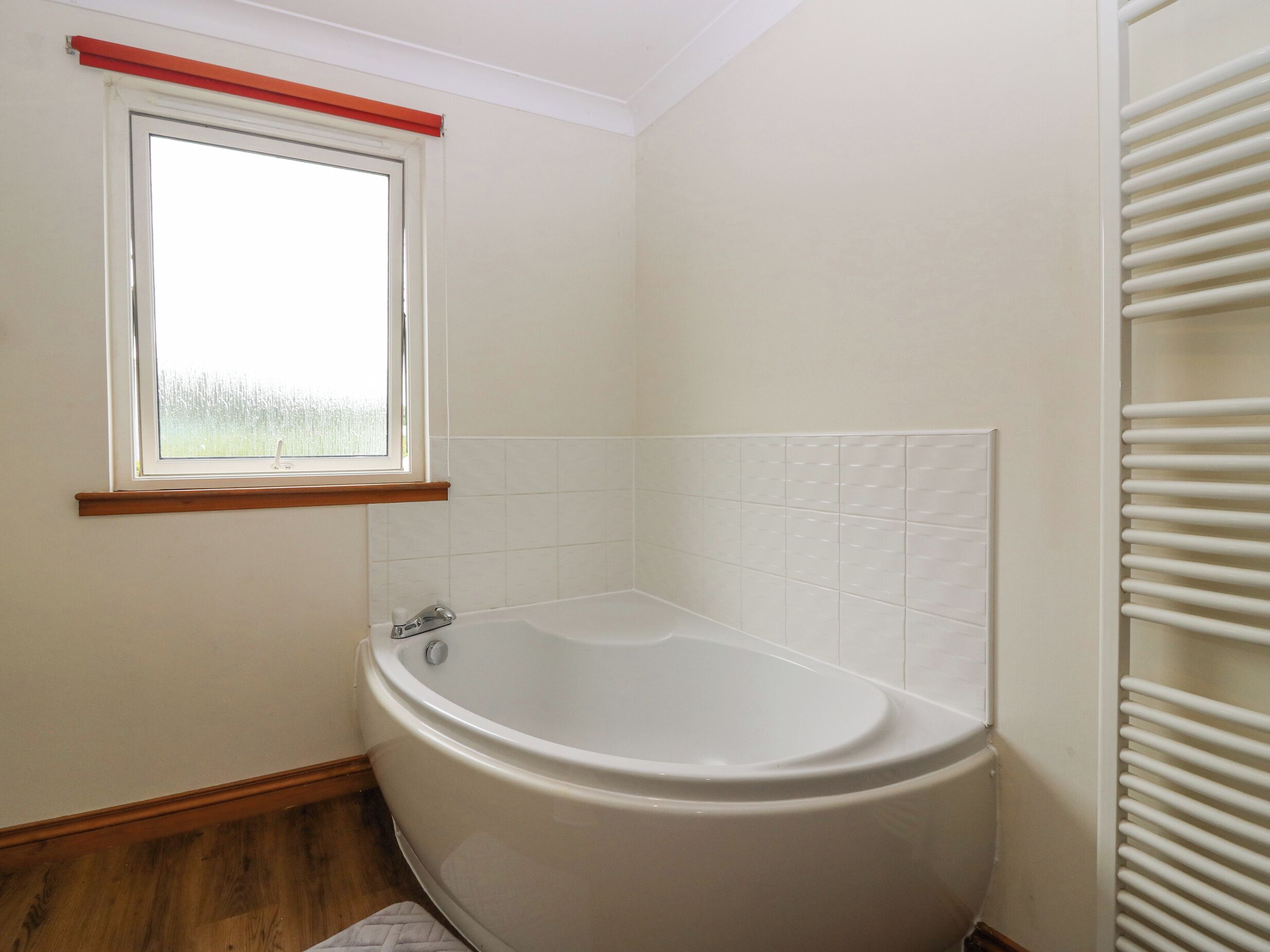 Een badkamer met een bad, een raam en een radiator.