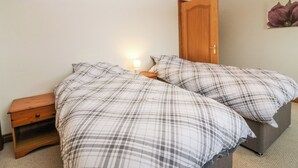 A bedroom with a bed, nightstand, and a door. - Hedgehogs Cottage (Glenrothes)