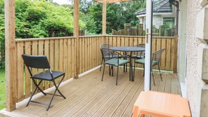 A wooden deck with a glass door leading to a patio area. - Hedgehogs Cottage (Glenrothes)