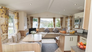 A cozy RV interior with a sofa, dining table, kitchenette, and large windows. - Ocean View (Ilfracombe)
