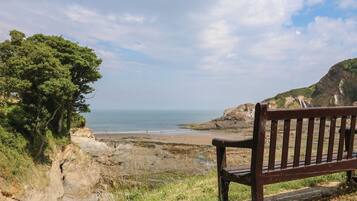 A bench overlooking a coastal landscape with cliffs and a beach.
