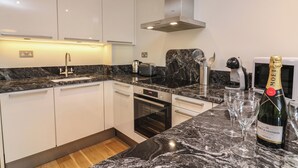 A modern kitchen with white cabinets, a black oven, and a marble countertop.