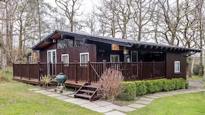 Eine Holzhütte mit Veranda, Grill und einer kleinen Treppe zum Eingang.
