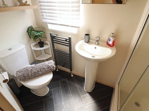 A small bathroom with a toilet, a sink, a towel, a plant, and a radiator. - 25 Kingfisher Court (Lincoln)