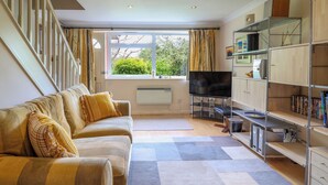 A living room with a sofa, TV, and shelves. - 50 Fernhill Heights (Bridport)