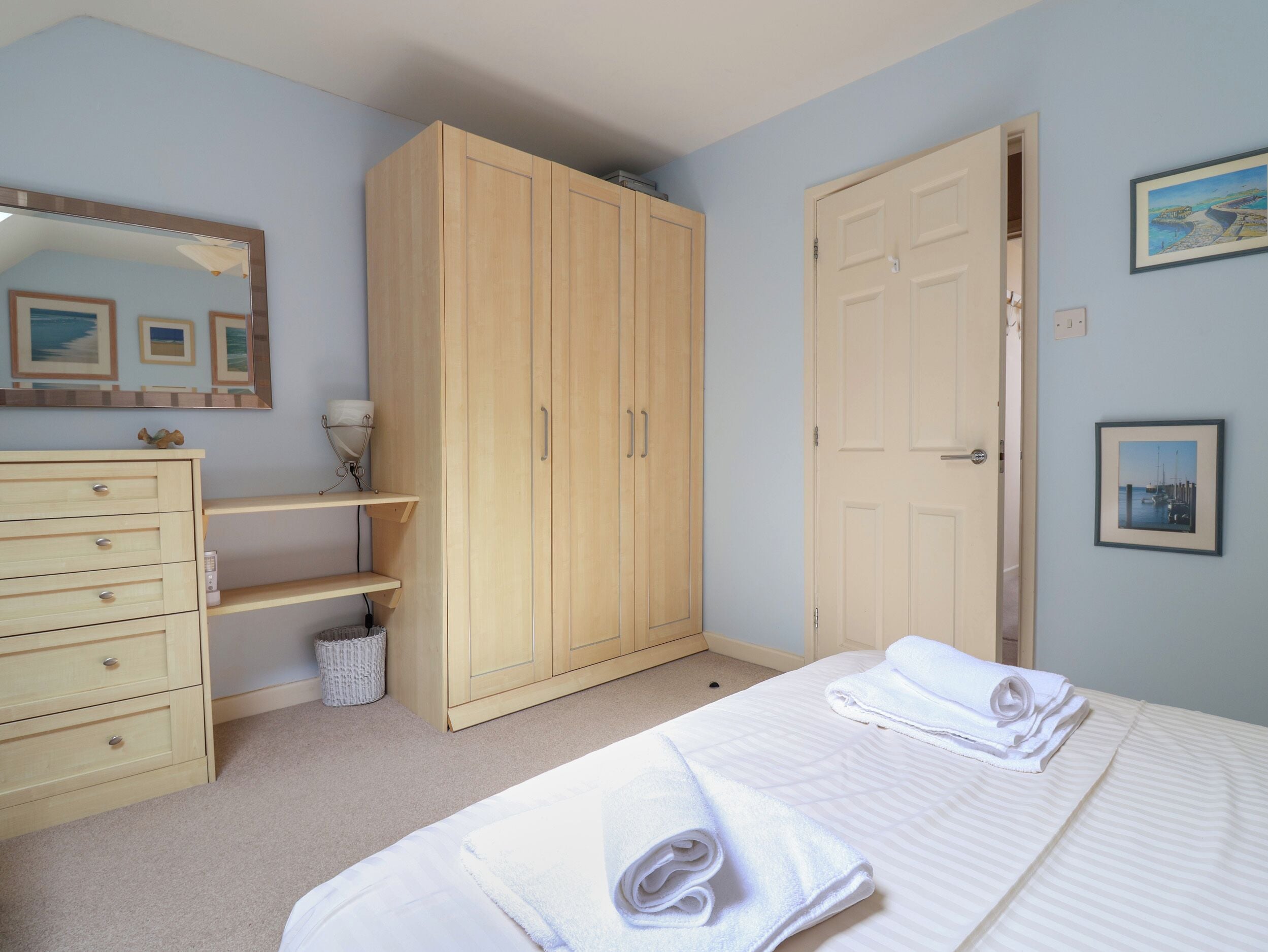 Une chambre à coucher comprenant un lit, une armoire, une commode, un miroir et une porte.