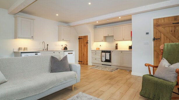 A modern kitchen with white cabinets, a built-in oven, and a dining area with a wooden table and chairs. - 8 Rookhaye (Salisbury)