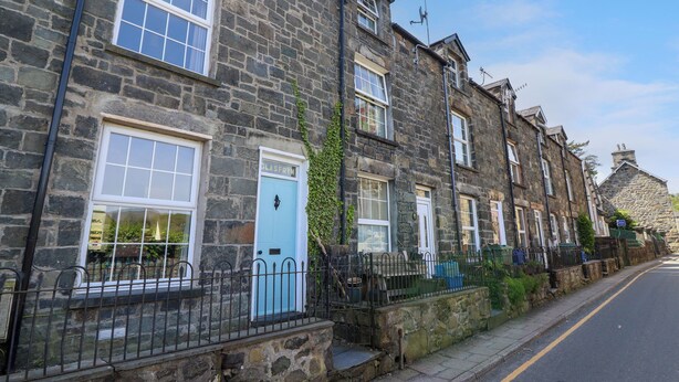 A row of stone buildings with traditional architecture, featuring multiple windows and doors, some with visible signage. - Glasfryn (Dolgellau)