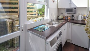 A modern kitchen with a built-in washing machine, a microwave, and a sink. - Glasfryn (Dolgellau)