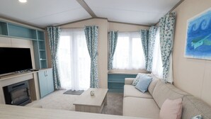 Ein modernes Wohnzimmer mit Flachbildfernseher, einer Couch, einem Couchtisch und einem Kamin.