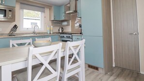 Eine moderne Küche mit einer zentralen Kochinsel, weißen Stühlen und einem eingebauten Backofen.
