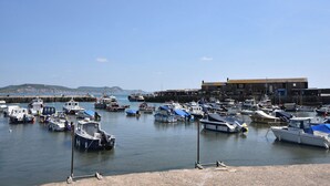 A marina with various boats docked, a building with a sign, and a clear sky. - 4 Lymbrook Cottages (Lyme Regis)