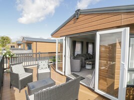 An open patio with wicker furniture, a glass door leading to a living area with sofas and a coffee table.