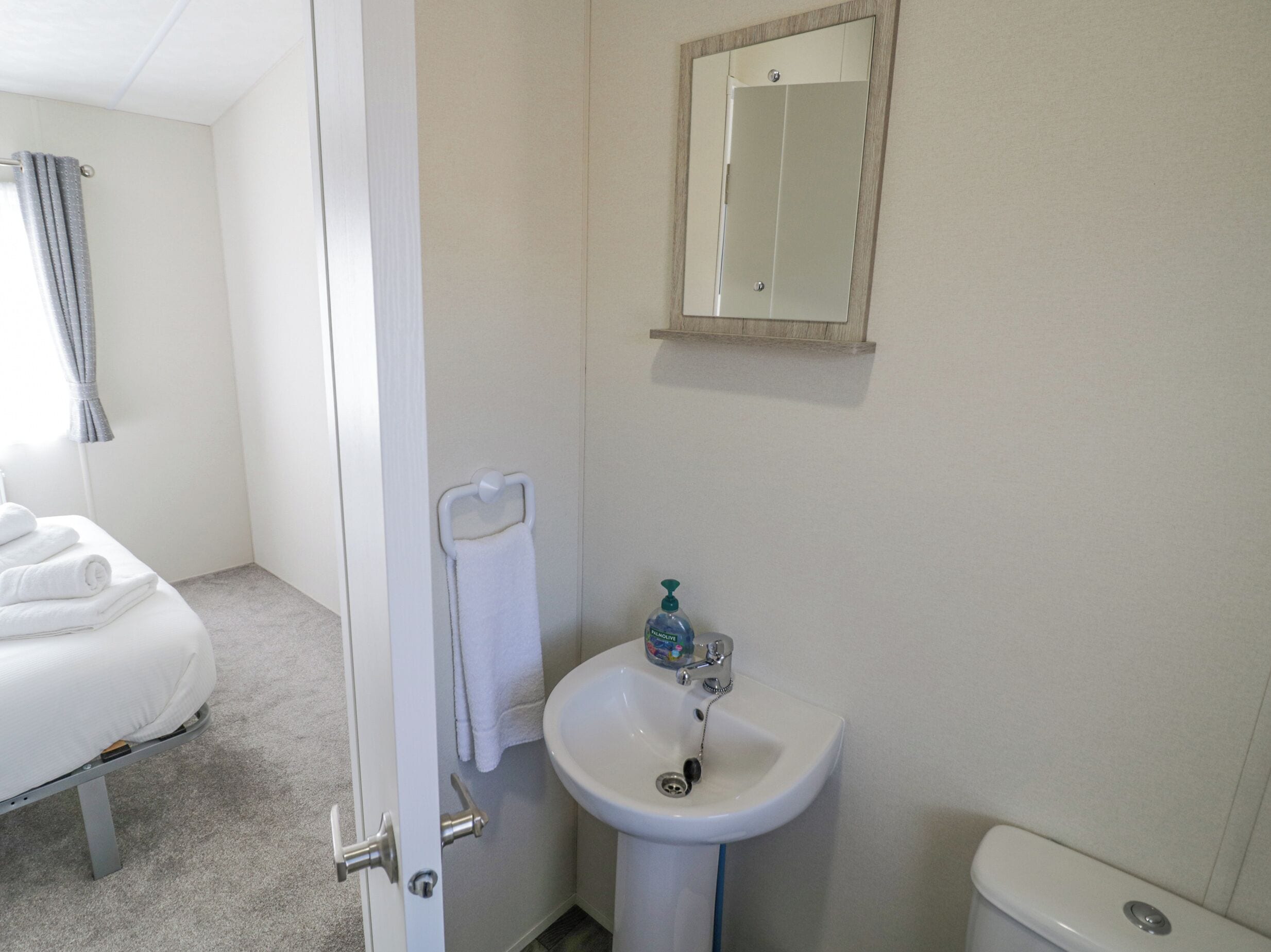 A hotel bathroom with a white sink, a mirror, and a toilet.