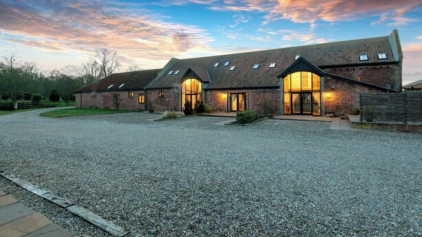 A large, modern building with multiple brick structures and large windows, surrounded by a gravel driveway. - Teal (Beccles)