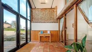 A room with large windows, a wooden table, and a potted plant. - Teal (Beccles)