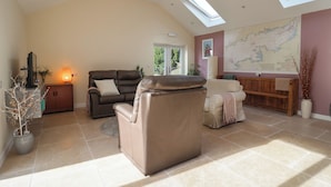 A spacious living room with a high ceiling, a large window, and a map on the wall. - The Lodge at Redlands (Lyme Regis)