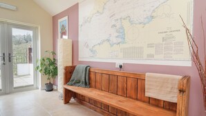 A room with a wooden bench, a large map on the wall, a potted plant, and a door leading to an outdoor area. - The Lodge at Redlands (Lyme Regis)