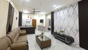 A modern living room with a sofa, a glass coffee table, and a TV stand. - SBHS Homestay - Vrushabadri (Tirupati)