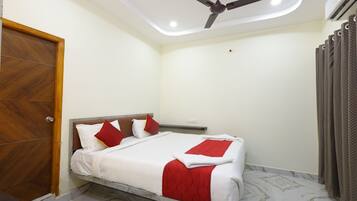A bedroom with a bed, a ceiling fan, a wooden door, and a curtain.