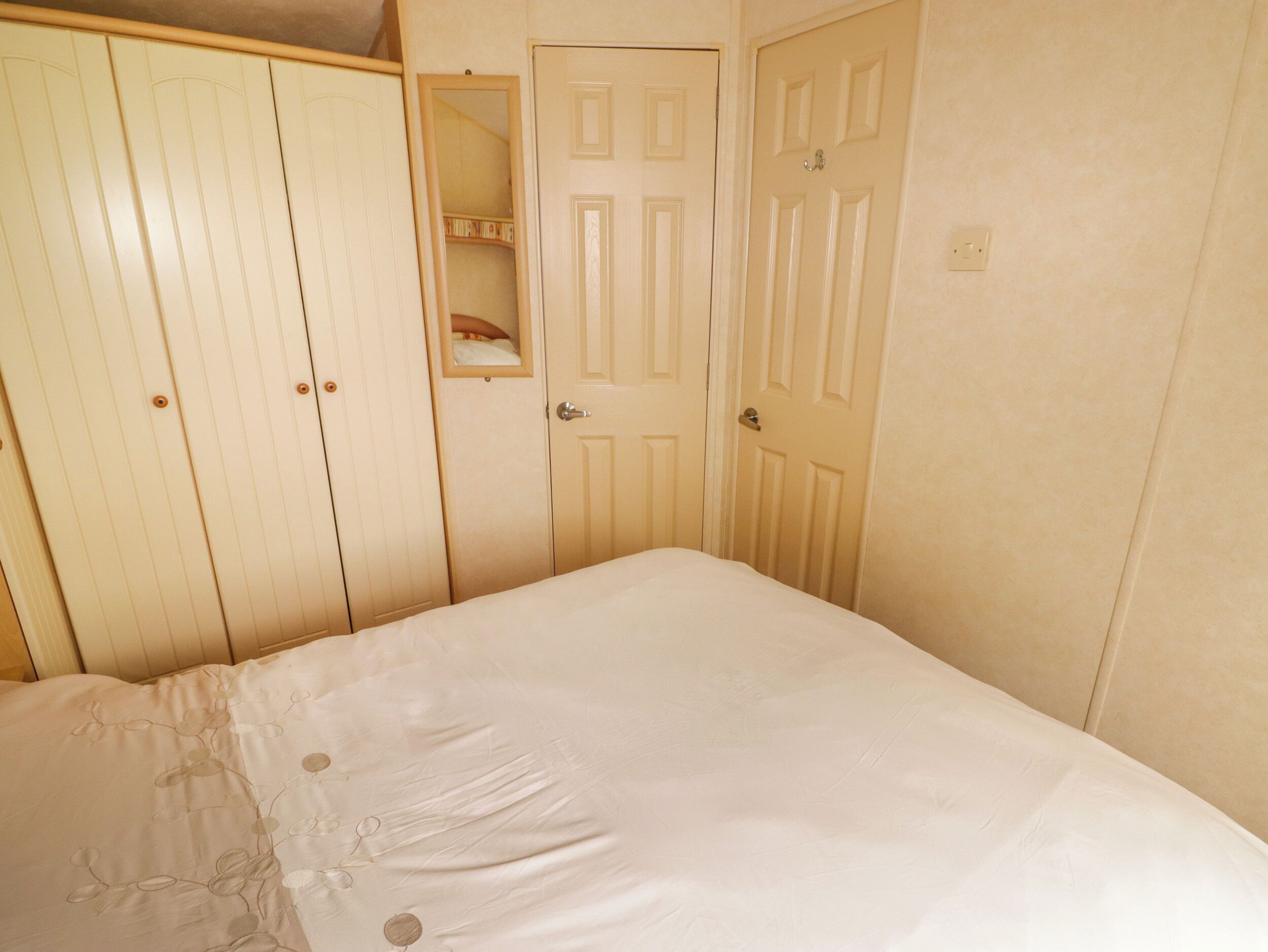 Un dormitorio con cama, armario y puerta con espejo.
